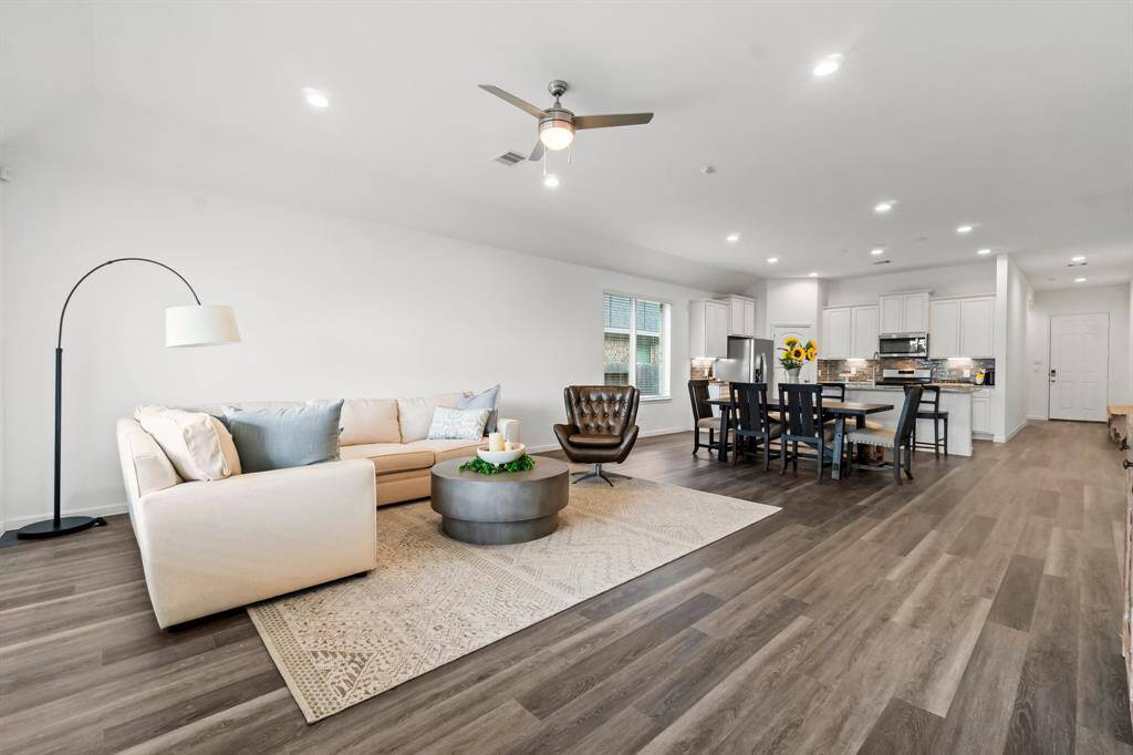 This is a spacious, open-plan living area with modern finishes, featuring a combined living room, dining room space, and kitchen with ample natural light.