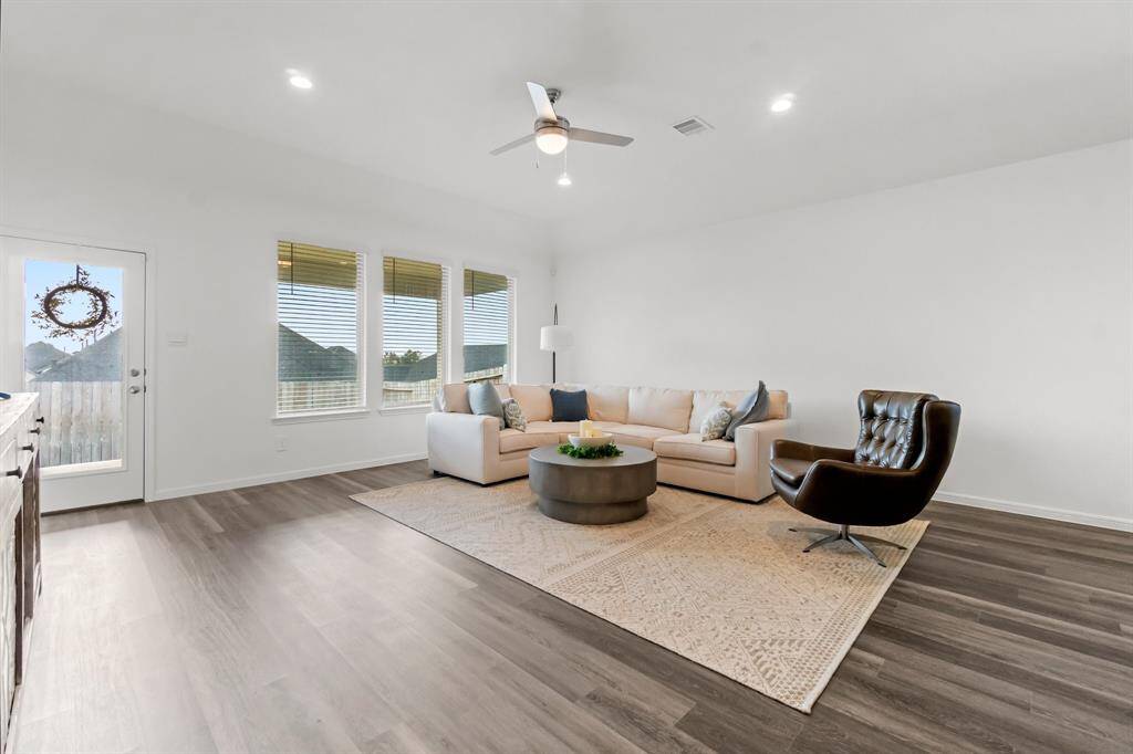 Living room featuring large windows with blinds throughout, modern wood flooring, and a neutral color palette.