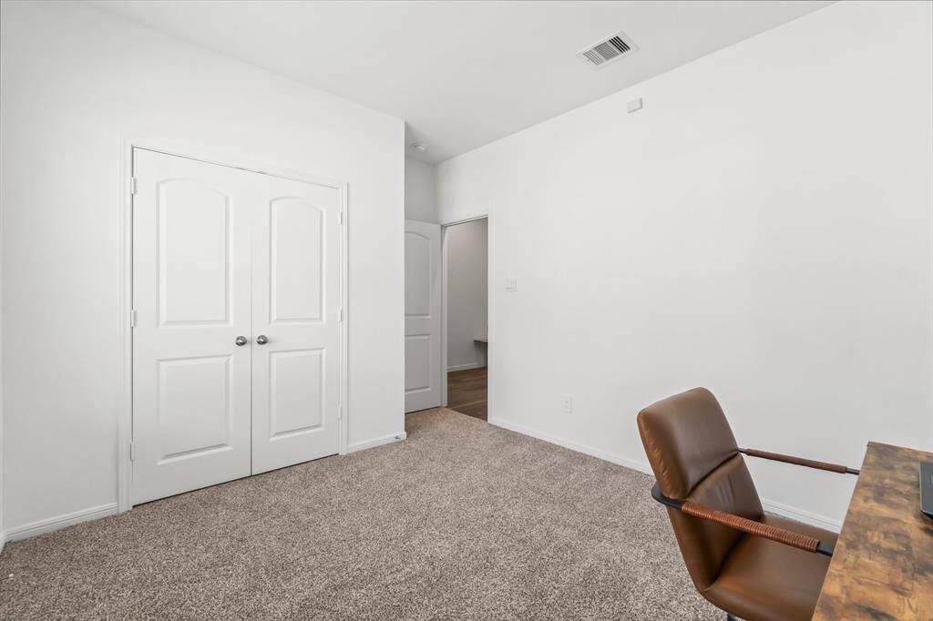 The front secondary bedroom offers a pleasant view of the hallway and includes ample closet space and soft carpeting, creating a comfortable and functional retreat.