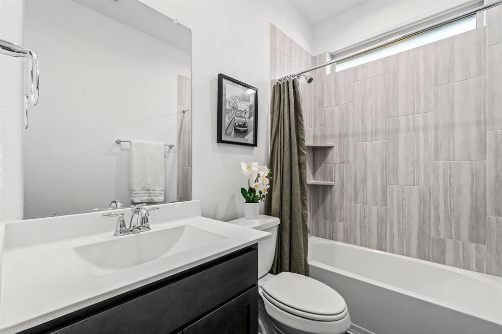The secondary bathroom features a single sink with ample counter space and a combined shower and tub, offering both style and functionality for everyday convenience.