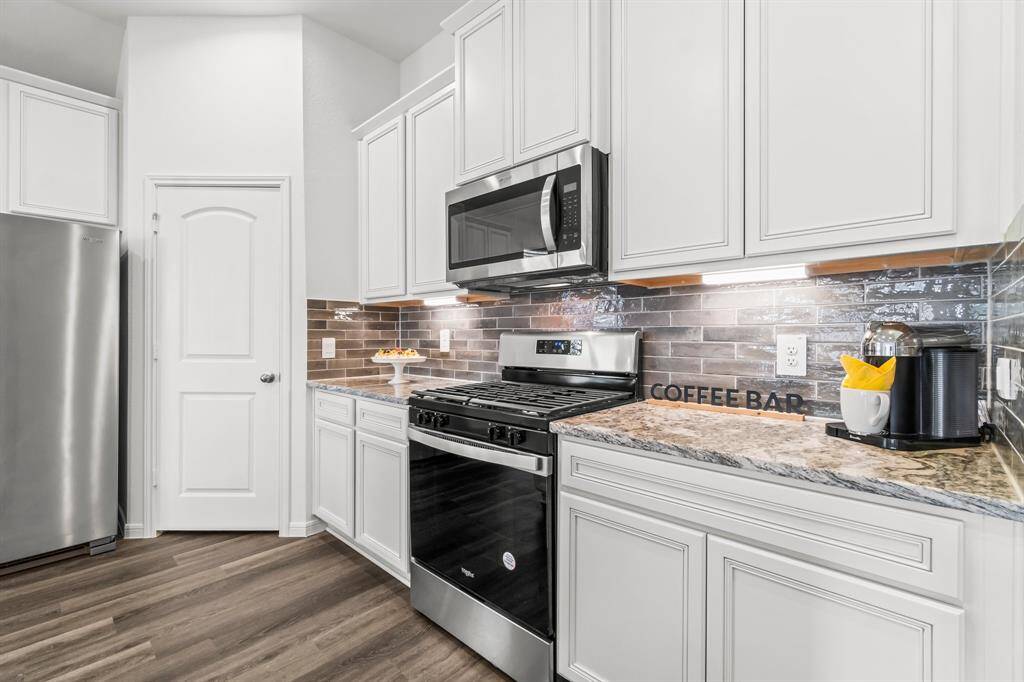 Enjoy this spacious kitchen with stainless steel appliances, white cabinetry, granite countertops, and a stylish backsplash. There's a designated coffee bar area.