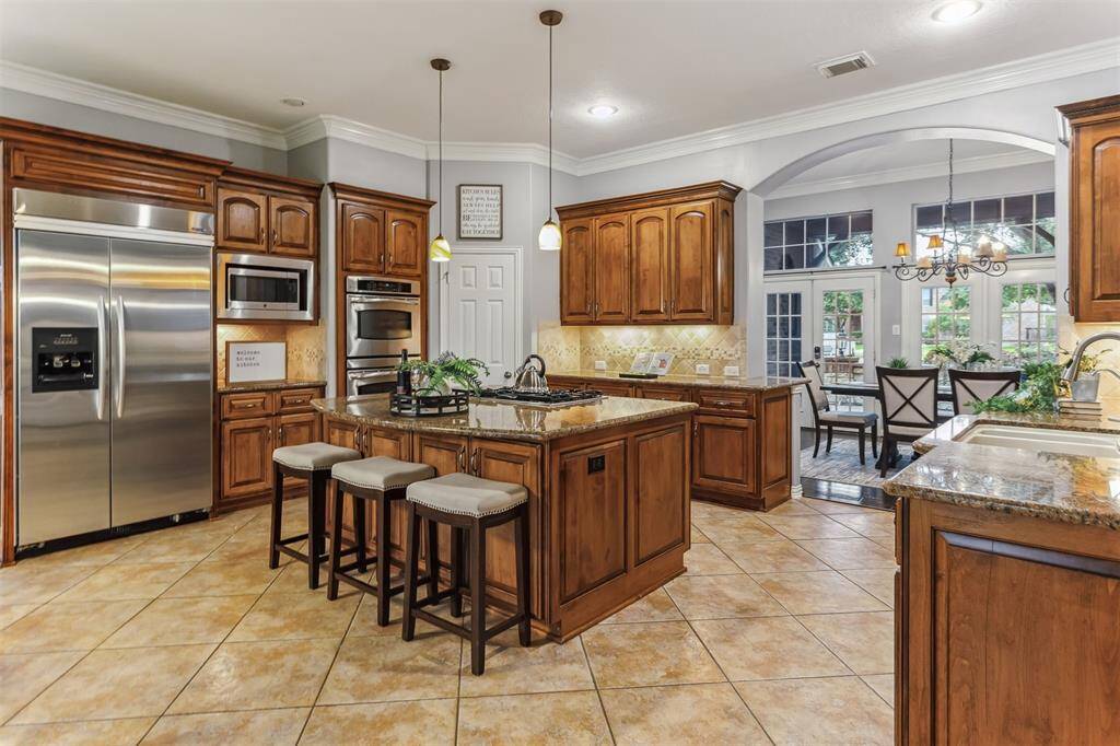 7014 Lake Haven Ct, Sugar Land Tx 77479-Adjacent to the kitchen is a bright and airy dining area, surrounded by large windows and French doors that open to the outdoor space, providing a seamless indoor-outdoor living experience. The arched entryway and detailed crown molding further enhance the sophisticated look of this kitchen, making it a perfect blend of style and functionality.