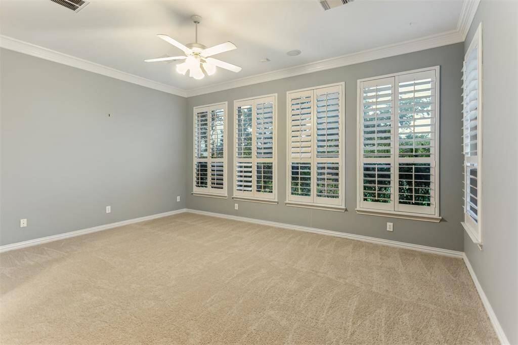7014 Lake Haven Ct, Sugar Land Tx 77479- This spacious and bright bedroom offers a serene retreat with its neutral color palette and plush carpeting. The room features large windows adorned with plantation shutters, allowing for adjustable natural light while providing privacy. The high ceiling is accented by elegant crown molding, and a ceiling fan ensures comfort year-round. This versatile space is ready to be transformed into your ideal bedroom oasis.Primary bedroom has new carpet!