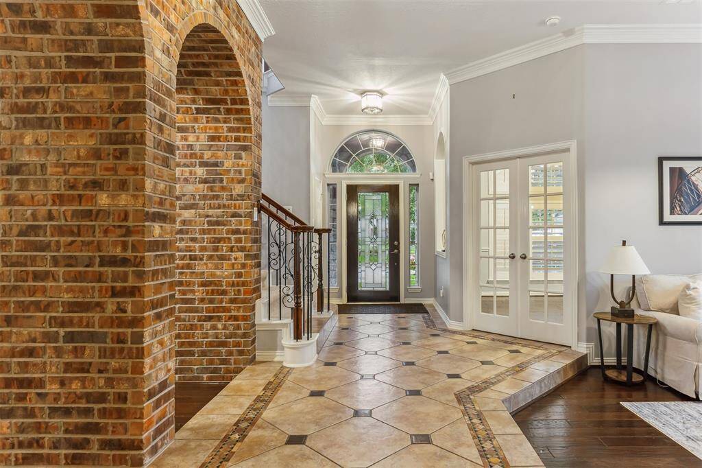 7014 Lake Haven Ct, Sugar Land Tx 77479-Welcome to a stunning entryway that seamlessly blends elegance and charm. As you enter, you're greeted by a beautifully tiled floor with intricate inlays that guide you through the space. The grand entrance features a stately front door with decorative glass panels, flanked by large windows that allow natural light to flood in, creating a bright and inviting atmosphere.