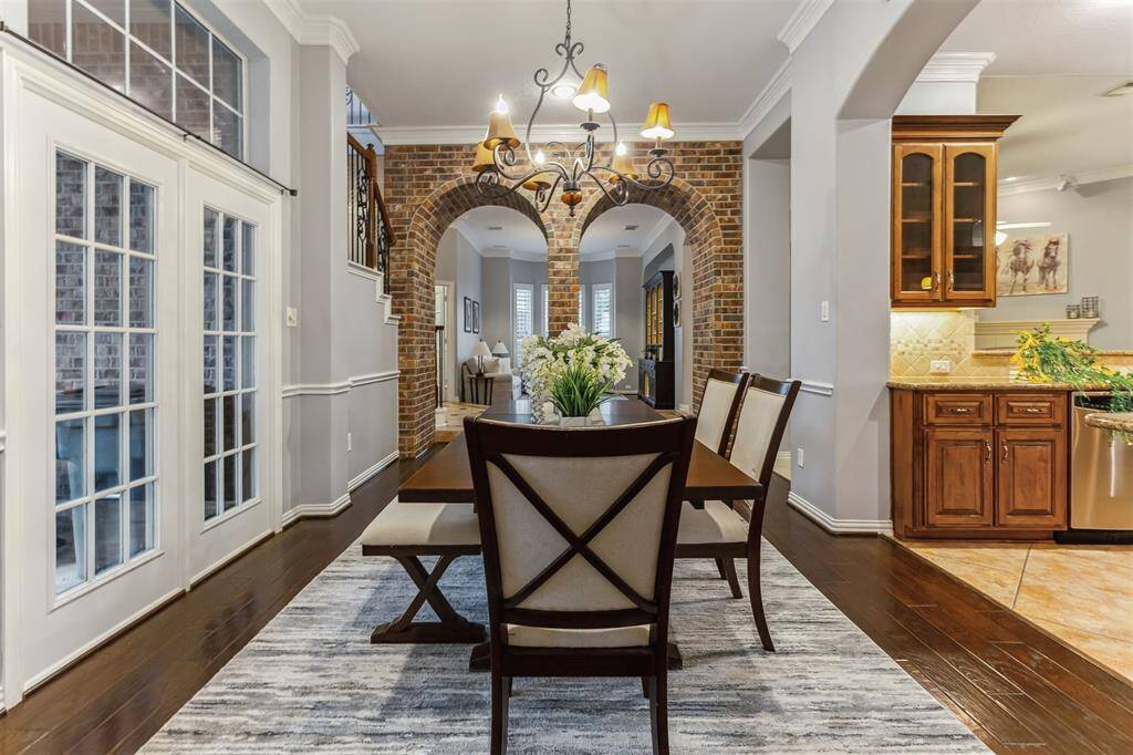 7014 Lake Haven Ct, Sugar Land Tx 77479-This elegant dining area showcases a sophisticated blend of architectural features and design elements. The room is highlighted by a graceful chandelier that adds a touch of luxury to the space. French doors with glass panels provide a seamless connection to the adjacent room, enhancing the open and airy feel.