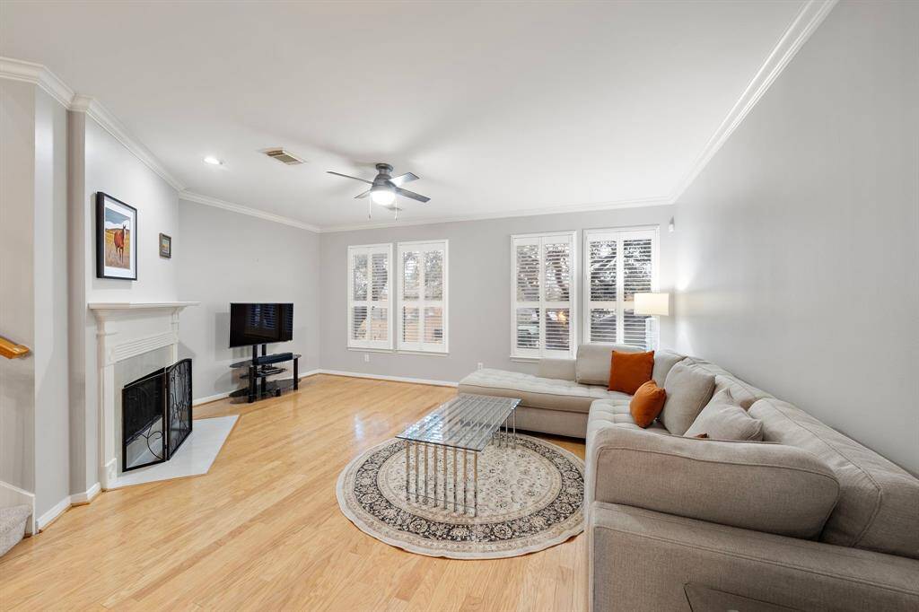 Filled with light, this comfortable living space is enhanced by plantation shutters and hardwood flooring. A decorative fireplace serves as a focal point.