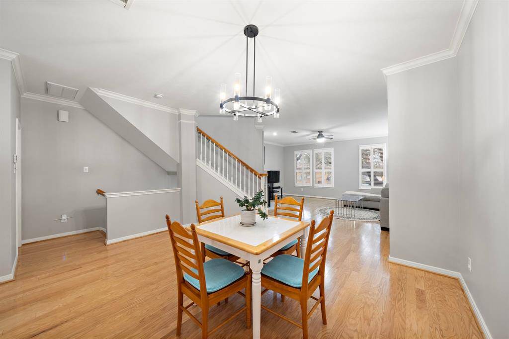 A sleek chandelier illuminates the dining area, complementing the open-concept layout. The hardwood flooring flows into the adjoining living spaces.