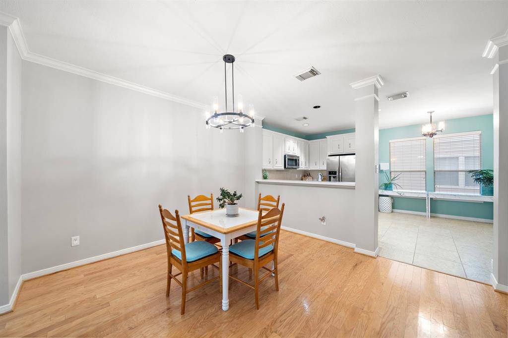 The dining area features wood floors and views into both the kitchen and additional living space.