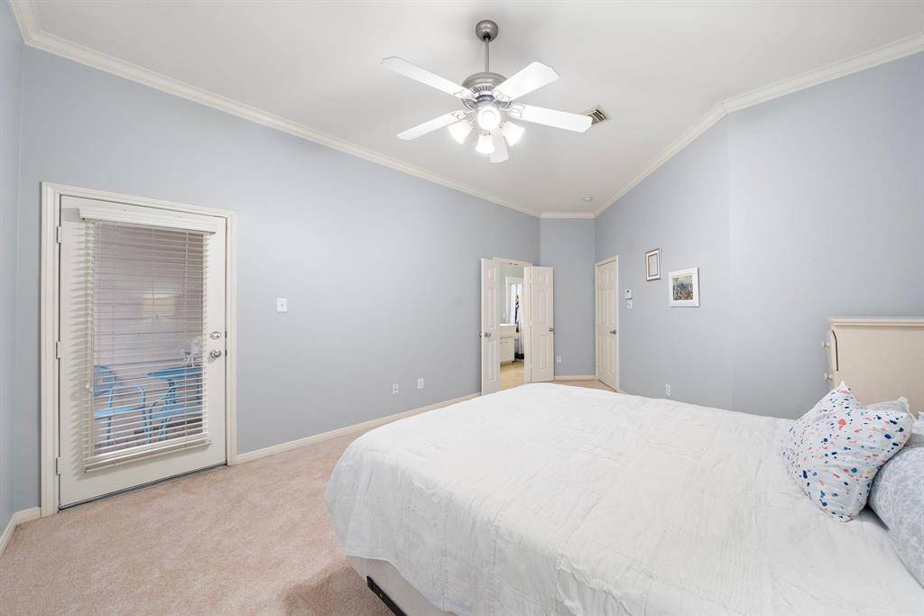 The primary bedroom provides neutral carpet flooring and french doors offer fresh air from a private patio, with a doorway to an ensuite bath and a walk-in closet.
