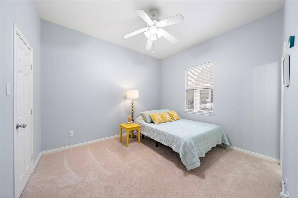Carpet flooring and sunlight streams through a window, enhance this second-floor bedroom's tranquil appeal for a relaxing retreat.