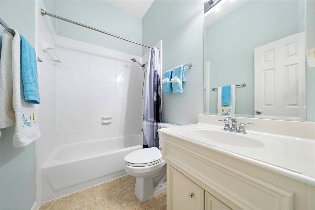 This full bath features a tub-shower combination, a single vanity, and abundant lighting to create a bright, tidy space.