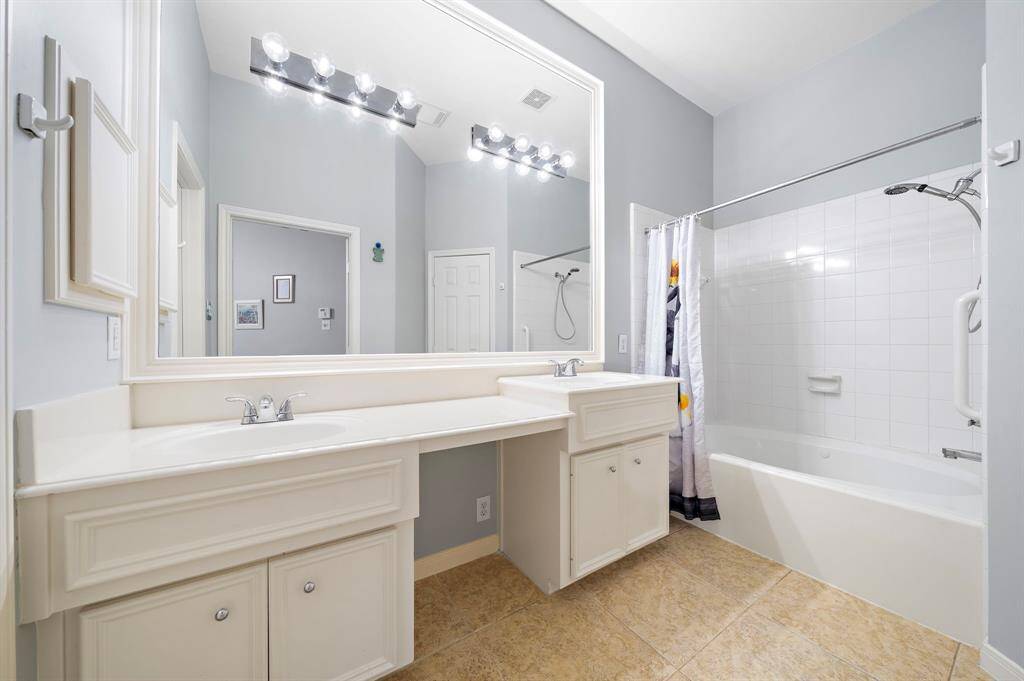 Dual sinks and a spacious countertop with storage below enhance the bathroom's functionality. The combined tub and shower offer a practical layout, suitable for everyday use.