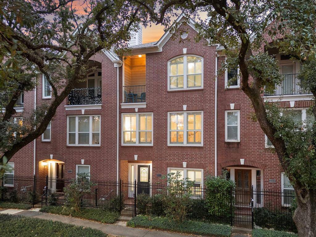 Showcasing the home's red brick facade, this 3-story townhome has a balcony and lush greenery enhancing the overall appeal.