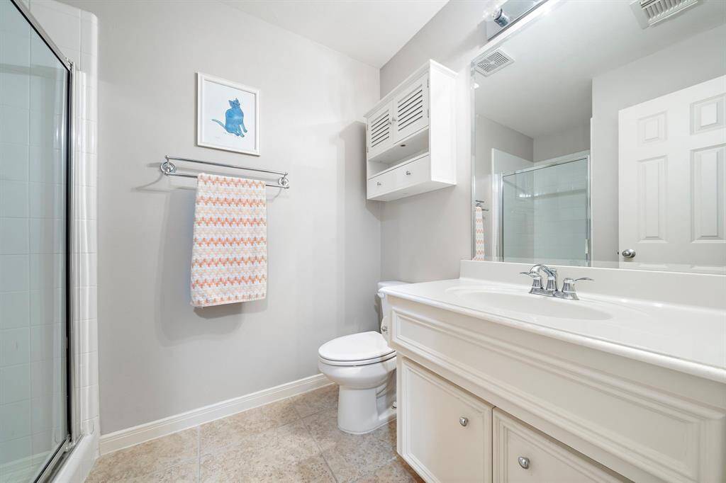 This bathroom delivers essential functionality with a tub-and-shower combination while upper and lower cabinets offer storage.
