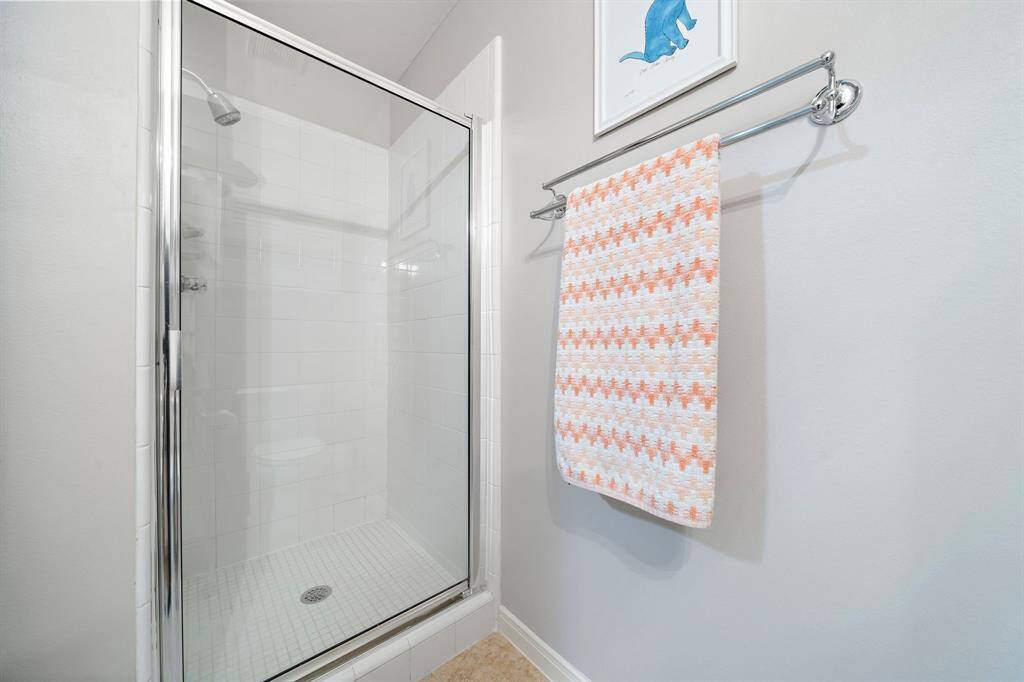 Practical functionality meets minimalist design in this full bath, showcasing a pristine shower, white tiling and a glass enclosure create a clean and bright space.