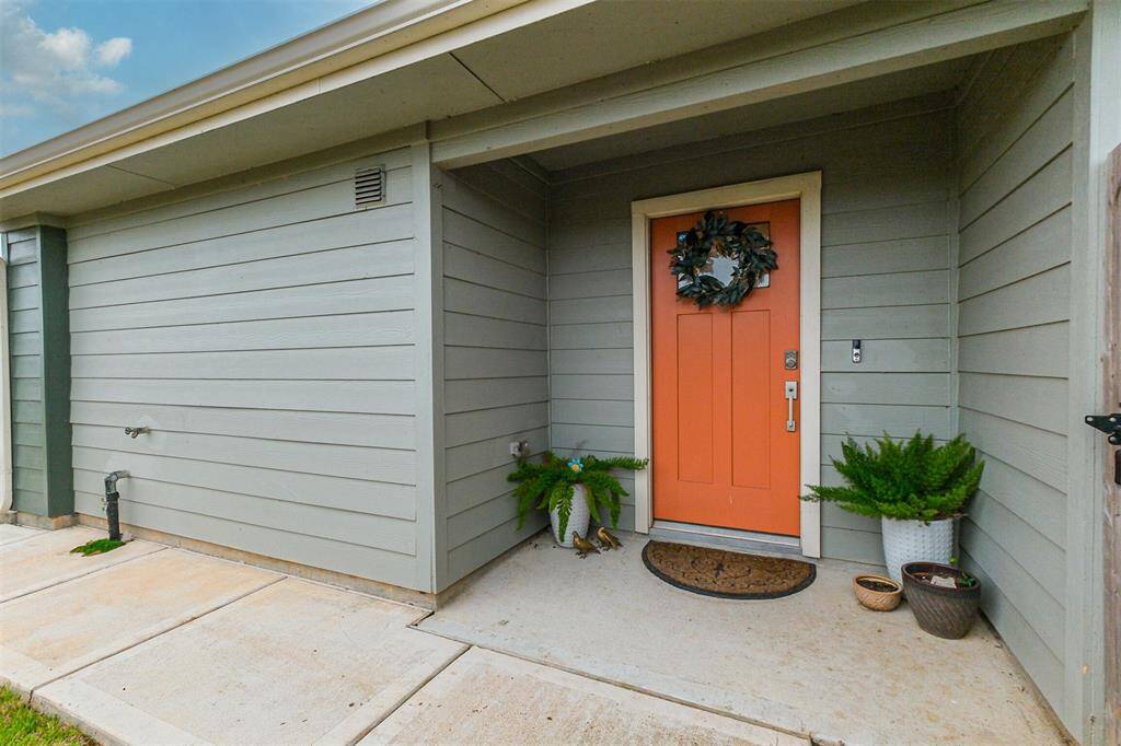 Tucked along the right side of this DR Horton home, the front entry boasts light gray Hardie-Plank siding and an inviting orange front door. The concrete walkway adds a clean and modern touch.
