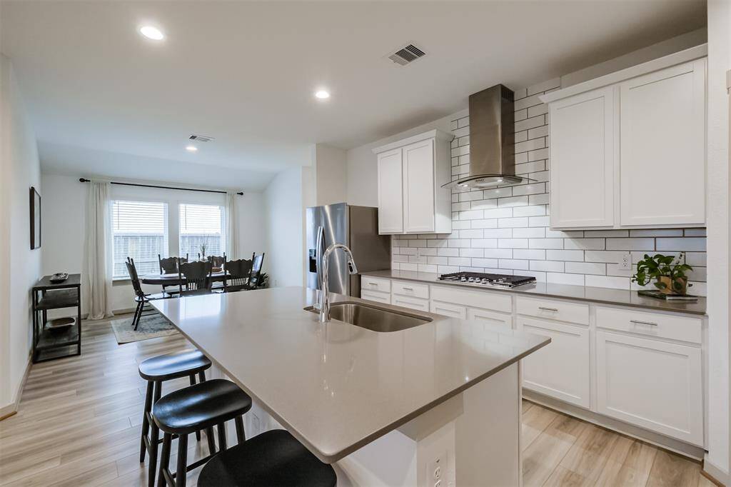 The home is anchored by a modern open-concept kitchenboasting sleek white cabinetry, all stainless appliances, and an impressive island with seating.