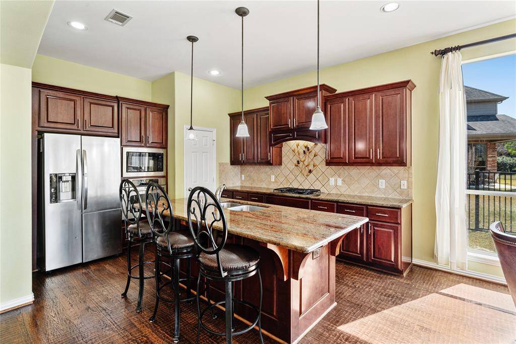 The gourmet island kitchen is a chef’s dream, featuring sleek granite countertops that offer both beauty and functionality. Stainless steel appliances provide modern convenience, while pendant lights add a stylish touch above the island. The custom hardware on the cabinets enhances the kitchen’s refined look, making it the perfect space for both cooking and entertaining.