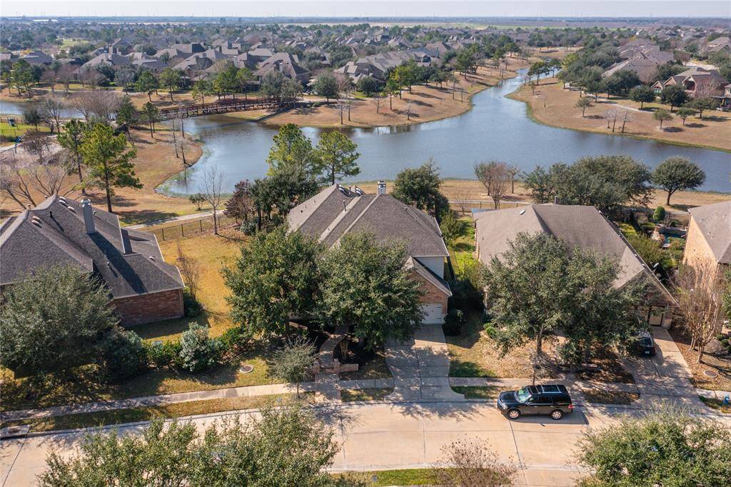 The aerial view perfectly captures the beauty of the home, with its elegant design nestled against the tranquil lake, offering an idyllic backdrop of shimmering water and lush greenery.