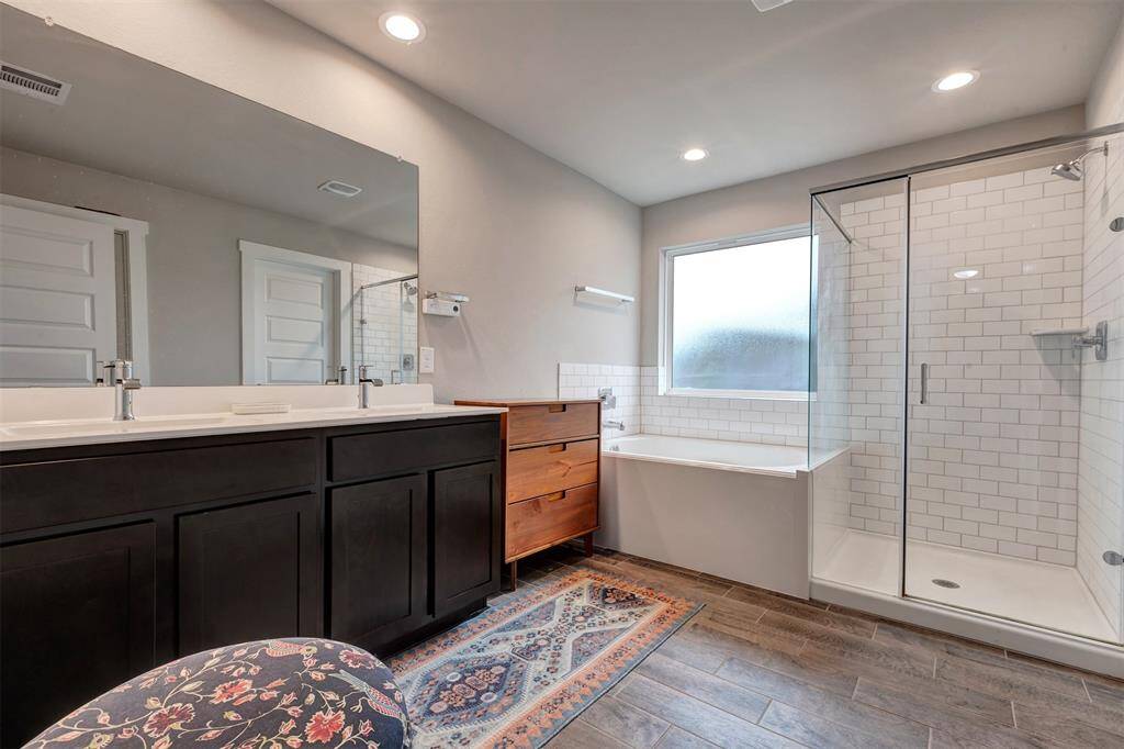 Spacious primary bedroom with a luxurious bath featuring a separate tub and glass-enclosed shower.