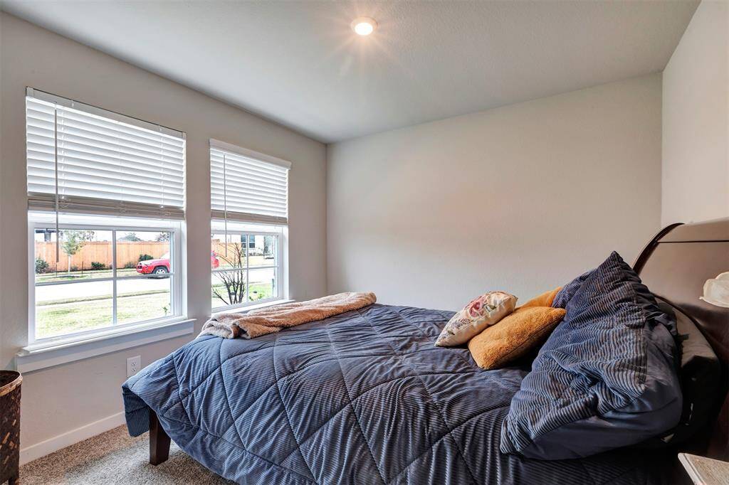 This bedroom located at the front of the house is filled with natural light from the large glass windows.