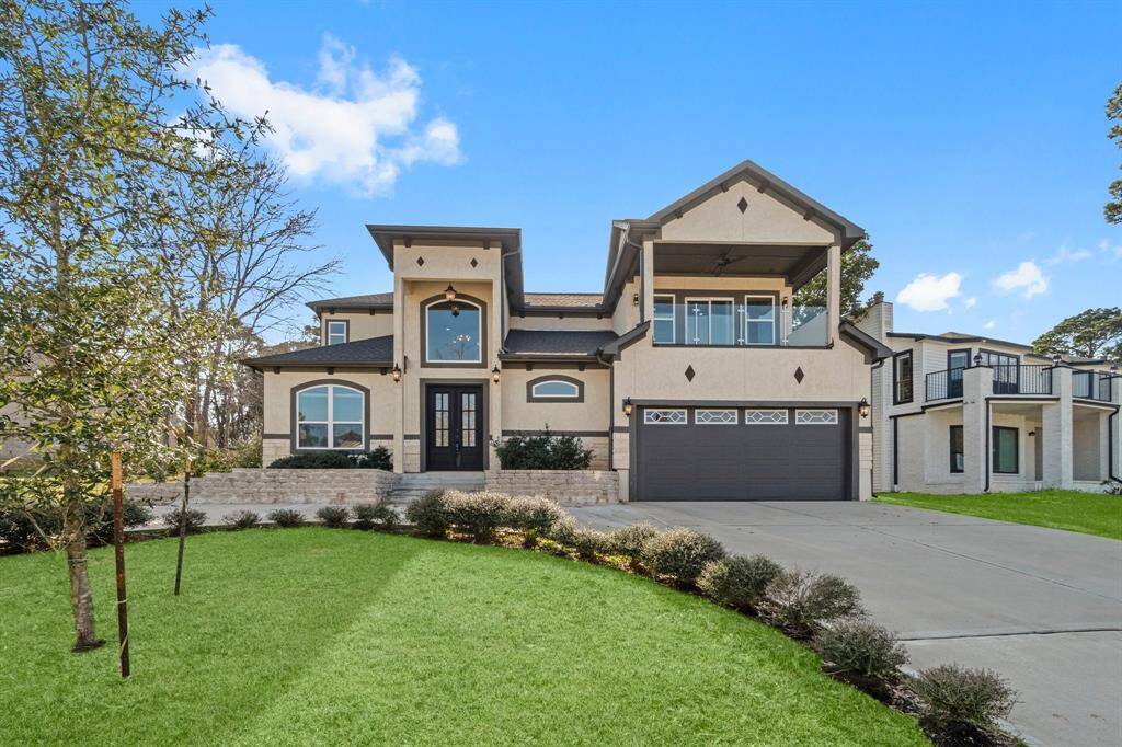 This modern two-story home features a spacious garage, large windows, and a welcoming front porch. The well-maintained lawn and driveway add to its curb appeal, while the upper balcony provides additional outdoor space.