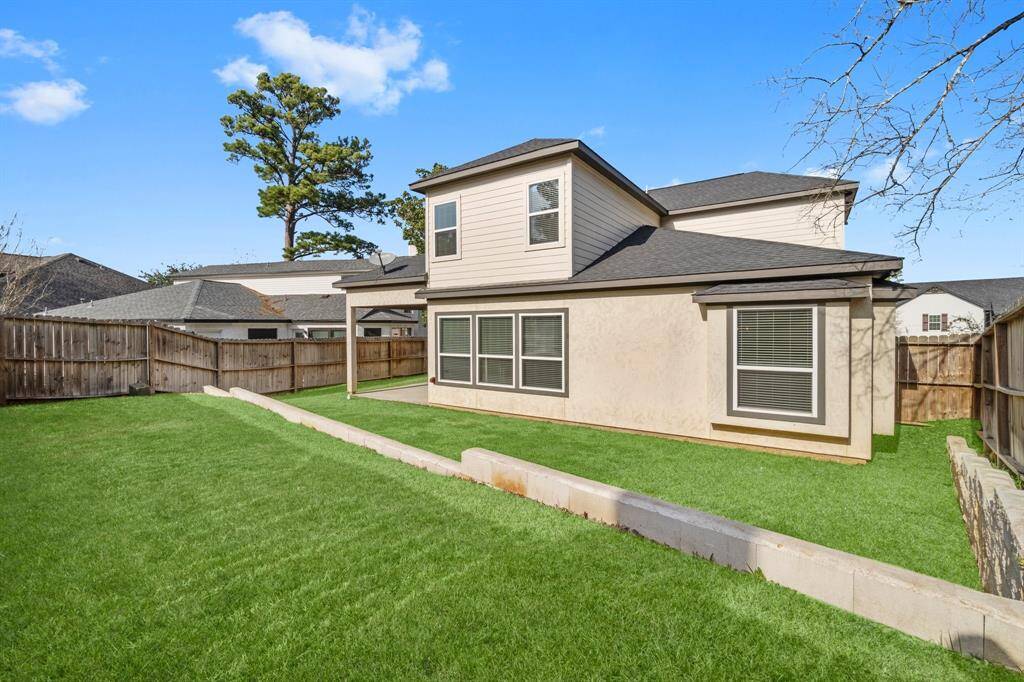 This photo shows a spacious backyard with a well-maintained lawn, surrounded by a wooden fence. The house features a two-story design with large windows, providing ample natural light. Ideal for outdoor activities and gatherings.