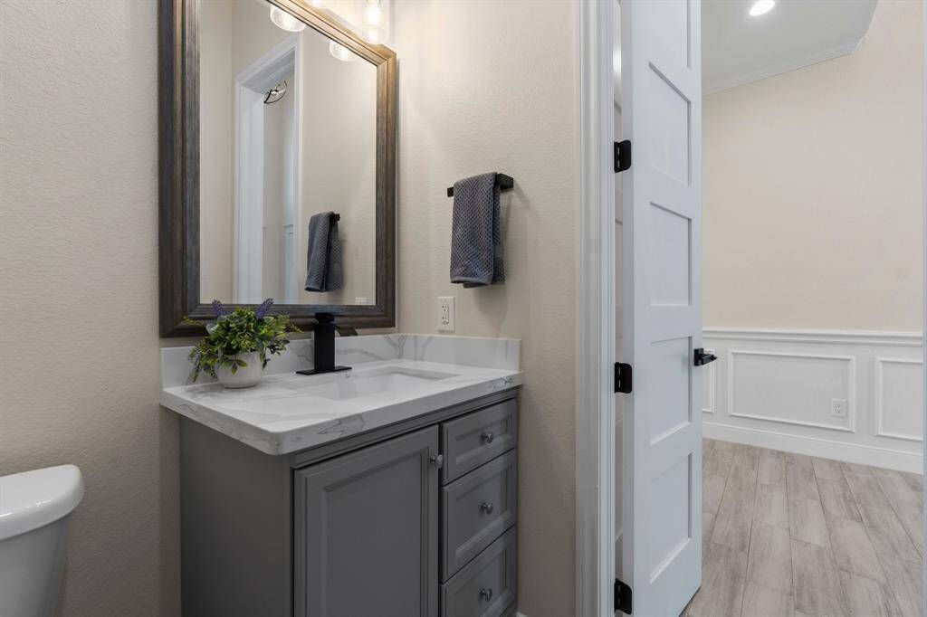 This photo shows a modern bathroom with a gray vanity, marble countertop, and a large framed mirror. It features a sleek faucet, neutral wall color, creating a clean and stylish look.