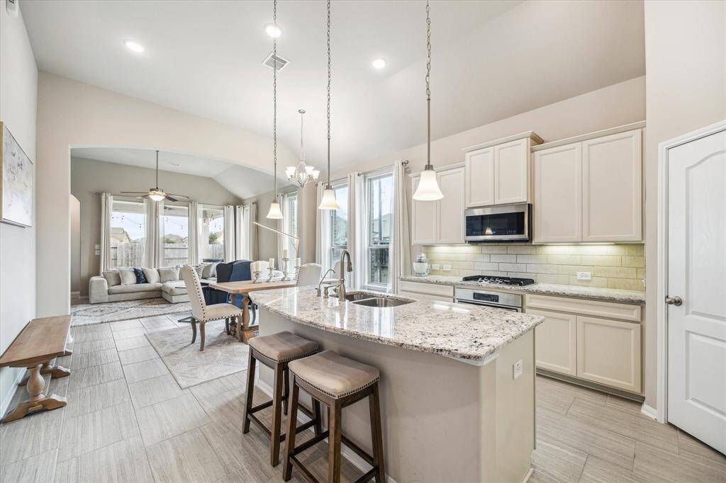 An island with bar seating separates the kitchen from the adjacent dining and living spaces.