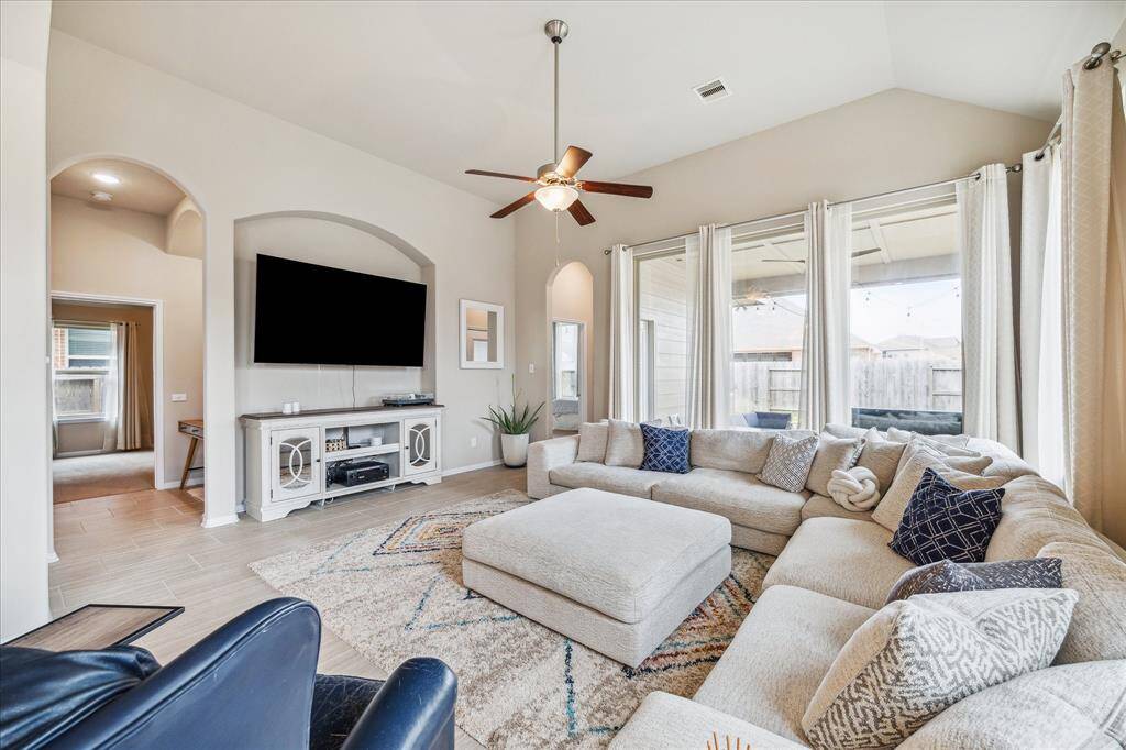 This bright, spacious living room features large windows, offering plenty of natural light and views of the backyard. The open layout and neutral tones create a welcoming atmosphere.