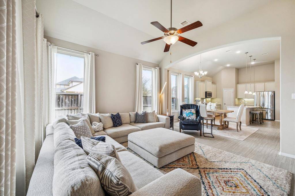 Another view of the living room showing how the space flows seamlessly into a dining area and a sleek kitchen, ideal for entertaining.
