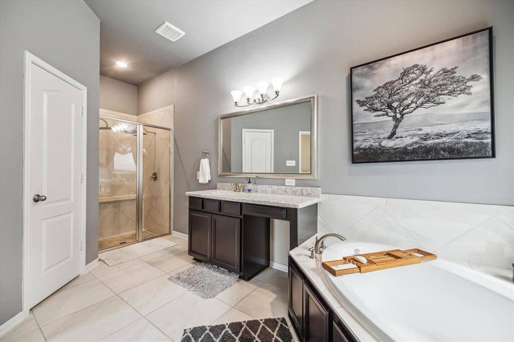 The Primary bathroom features a dual-sink vanity. The neutral color palette is complemented by modern fixtures and a large framed mirror.