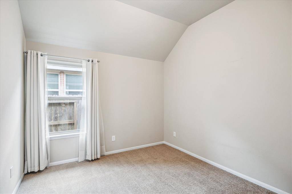 One of two secondary bedrooms features neutral walls, carpeted flooring, generous closet and a window with curtains, offering a cozy and bright space.