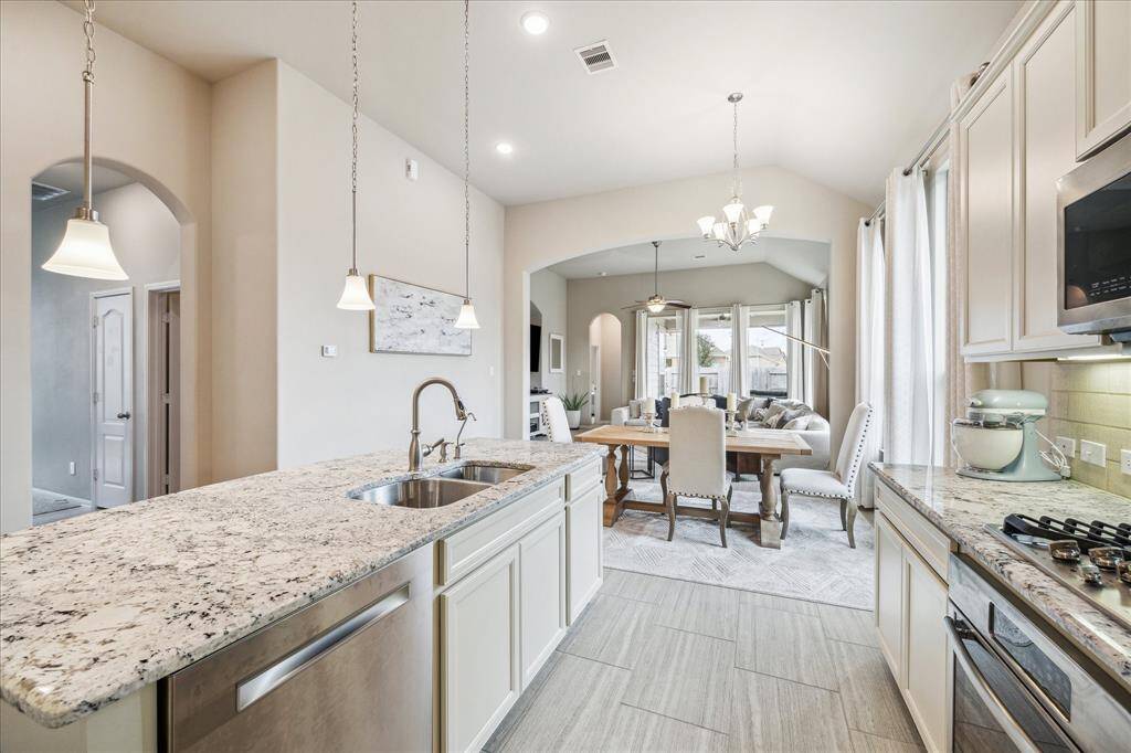 View of the bright, open-concept kitchen and dining area. The space flows into a cozy living area with large windows, offering plenty of natural light.