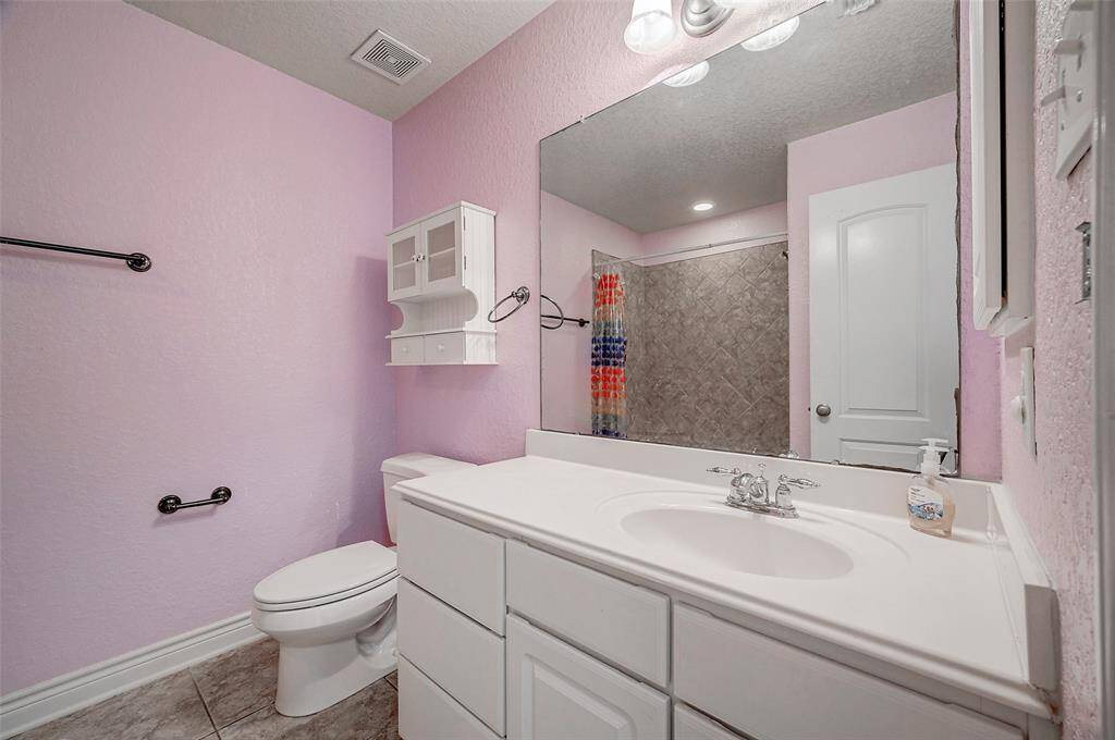 This secondary bathroom, located to the left of the game room, features light and bright LED lit fixtures, a spacious vanity area with a sink, ample storage with a full-sized tub / shower  combination. The additional wall-mounted cabinetry provides alternate storage area for improved organization.