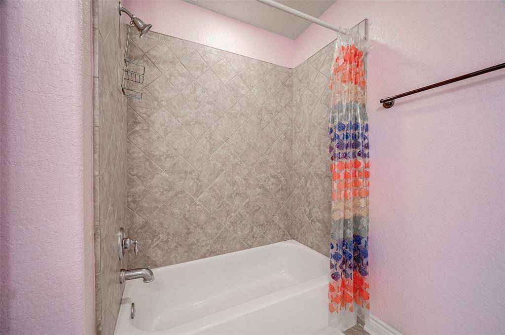 This is a cozy bathroom, located to the left of the game room, featuring a bathtub with overhead shower, LED lighting with neutral diamond tile pattern.  The tub / shower combination offers convenient options for shower or a relaxing tub soaking.