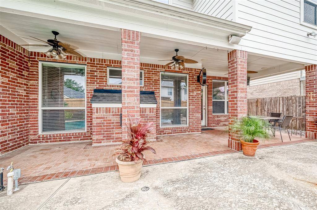 This spacious covered patio is accented with surround sound built-in overhead speakers, LED lit outdoor grade ceiling fans, and brick flooring, complementing a entire outdoor seating area overlooking the custom swimming pool and hot tub area.