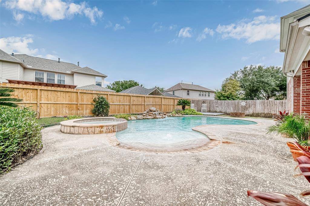 This area showcases the spacious backyard with an inviting in-ground pool and attached spa, surrounded by a privacy fence and complemented by your personalized rock waterfall fountain. The area is ideal for, sunbathing, relaxation and all outdoor entertainment.