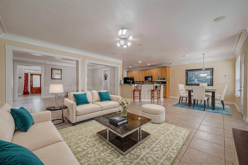 This interior space features an open floor plan with tiled flooring for ease of cleaning, elegant columns, and a seamless transition from the living area to the kitchen. The room is bright, with natural and LED lighting offering ample space for dining and entertainment.(Virtual Stage)