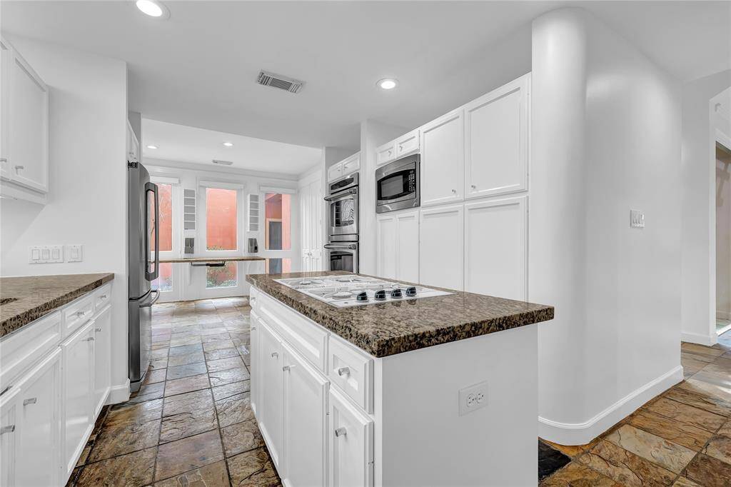 Kitchen with stainless steel appliances, white cabinetry, granite countertops, and a central island.