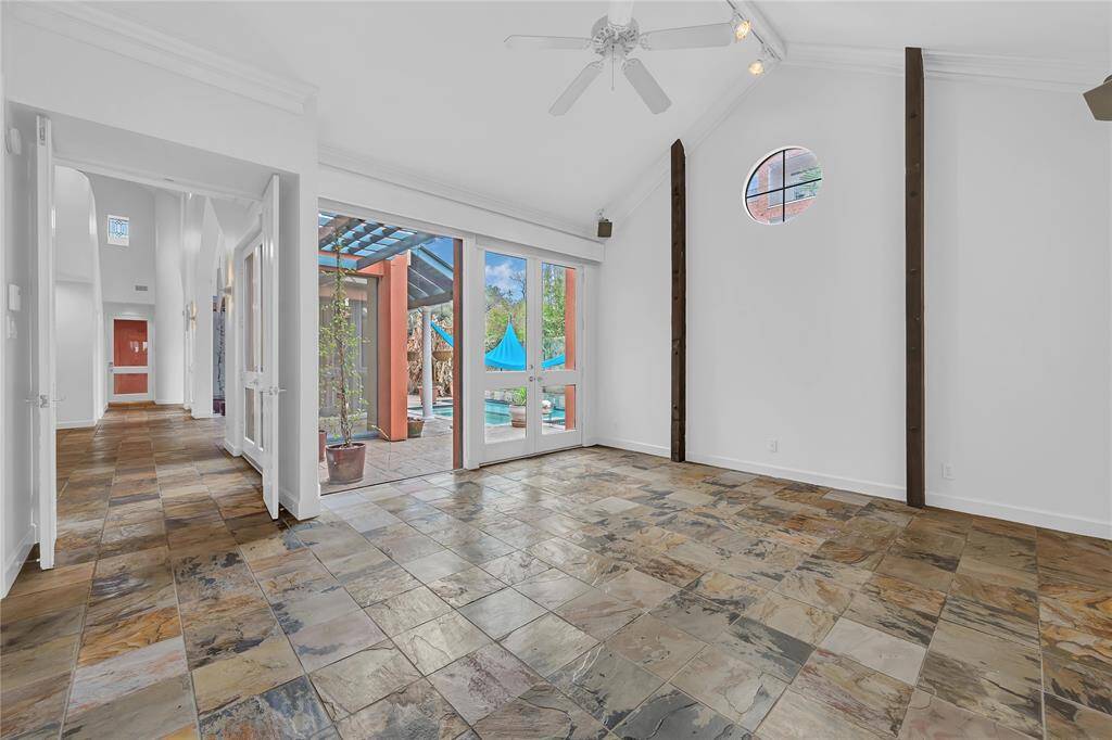 Primary suite with vaulted ceilings, tile floors and doors that lead out to the sparkling pool.
