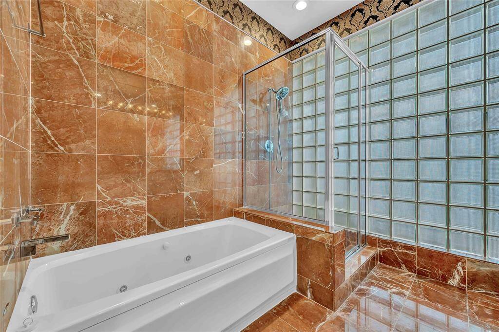 Primary bath with jetted tub and glass shower.