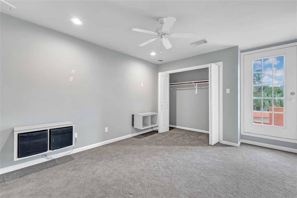Secondary bedroom upstairs features carpeted flooring, a ceiling fan, and plenty of natural light.
