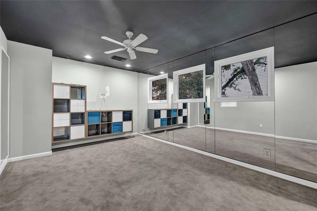 Secondary bedroom upstairs features carpeted flooring, ceiling fan, and walk-in closet with mirror on front.