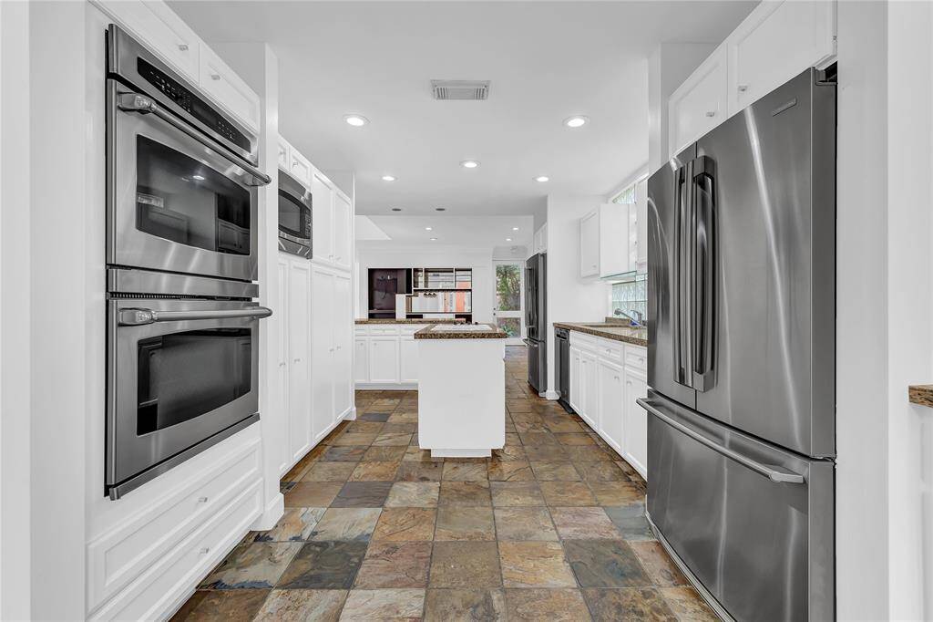 Kitchen includes stainless steel appliances, double ovens, island cooktop, and two refrigerators.