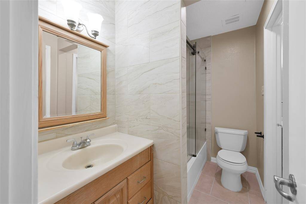 Bathroom with a modern shower enclosed in sleek glass doors and a beautiful new mirror above the sink.