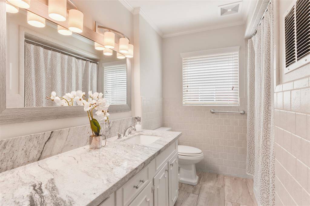 Conveniently accessible for secondary bedrooms and guests, this guest bathroom offers a large vanity with plenty of storage, granite countertop, a decorative mirror with vanity lights, and a tub/shower combination for ultimate functionality.