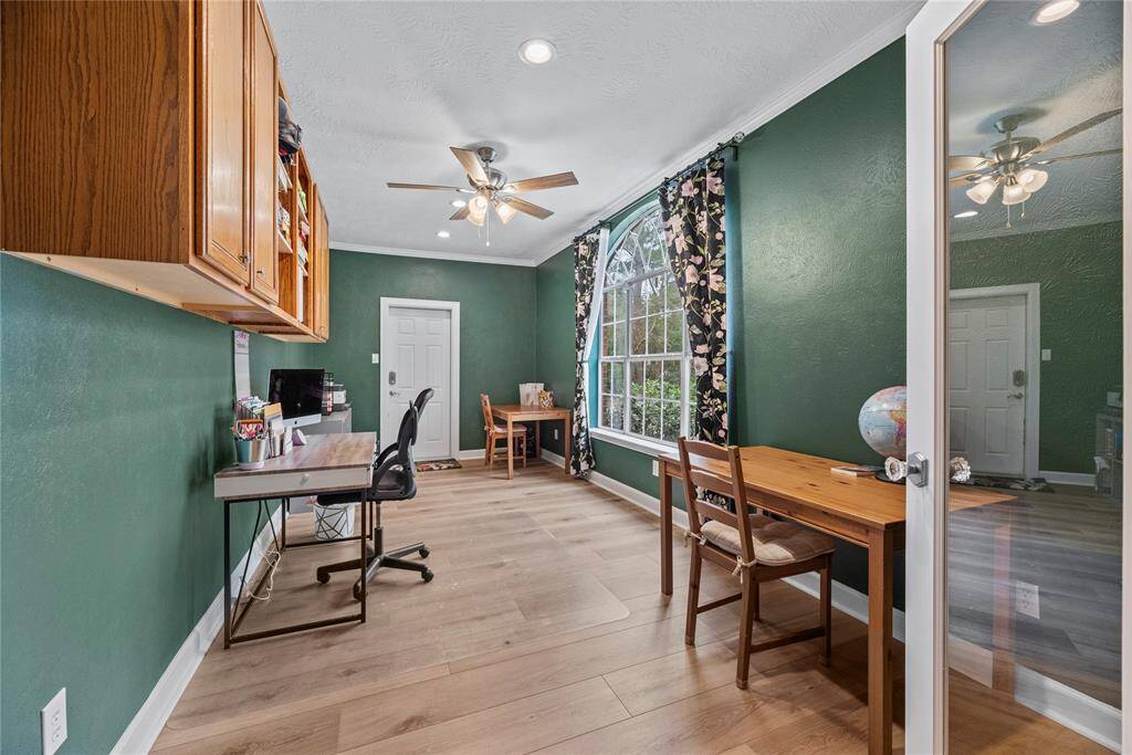 This versatile bonus room adapts to your needs, tucked behind elegant glass French doors. It showcases beautiful vinyl plank flooring, designer paint with crown molding, custom cabinetry, and plenty of space for your ideal setup.