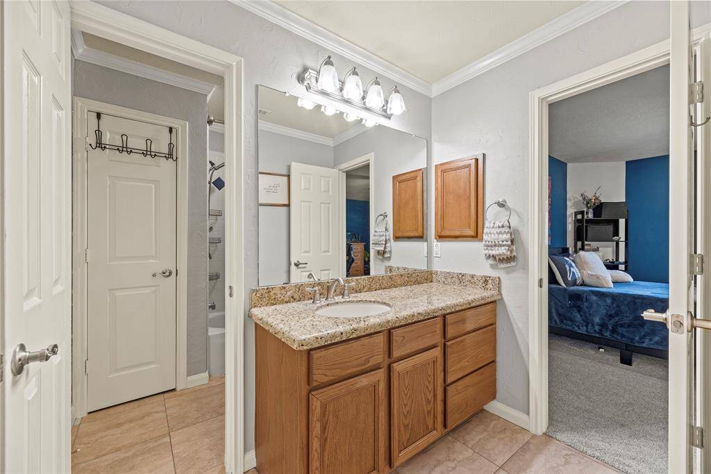 This spotless guest bathroom is accessed through both the guest suite and the game room. It offers a dressing area with a single sink vanity and a separate private water closet with a fully tiled tub/shower enclosure, a linen closet and toilet.