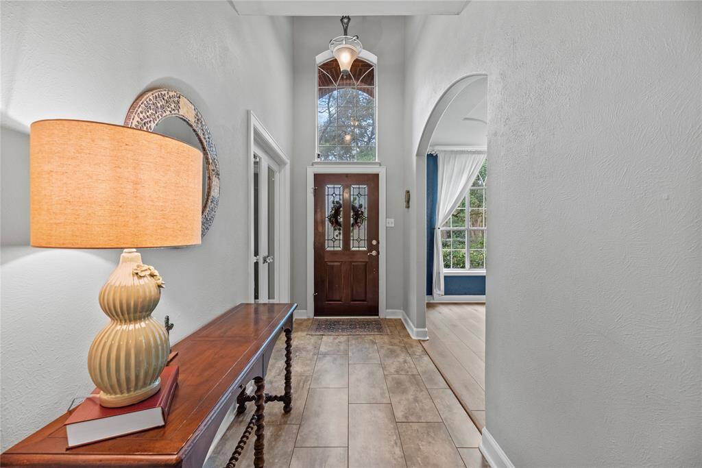 This dramatic foyer is a fabulous space to greet visitors with tile flooring, neutral paint, and a soaring ceiling with a stylish chandelier, setting expectations for a warm and inviting home.